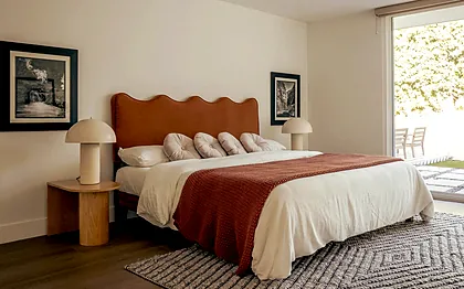 Ladera Heights bedroom with a rust velvet scalloped headboard and paired dome lamps, staged by Nesting Dolls Design