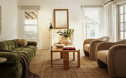 Larchmont 1920s living room with a green chenille sofa, velvet armchairs and an original carved marble mantel, staged by Nesting Dolls Design