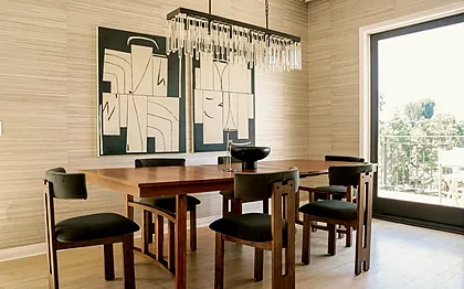Laurel Canyon dining room with a walnut table, olive velvet chairs and a black and white diptych on grasscloth walls, staged by Nesting Dolls Design