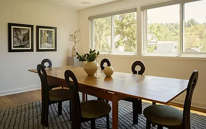 Sherman Oaks dining room with black keyhole-back chairs in olive velvet around a teak extending table, staged by Nesting Dolls Design