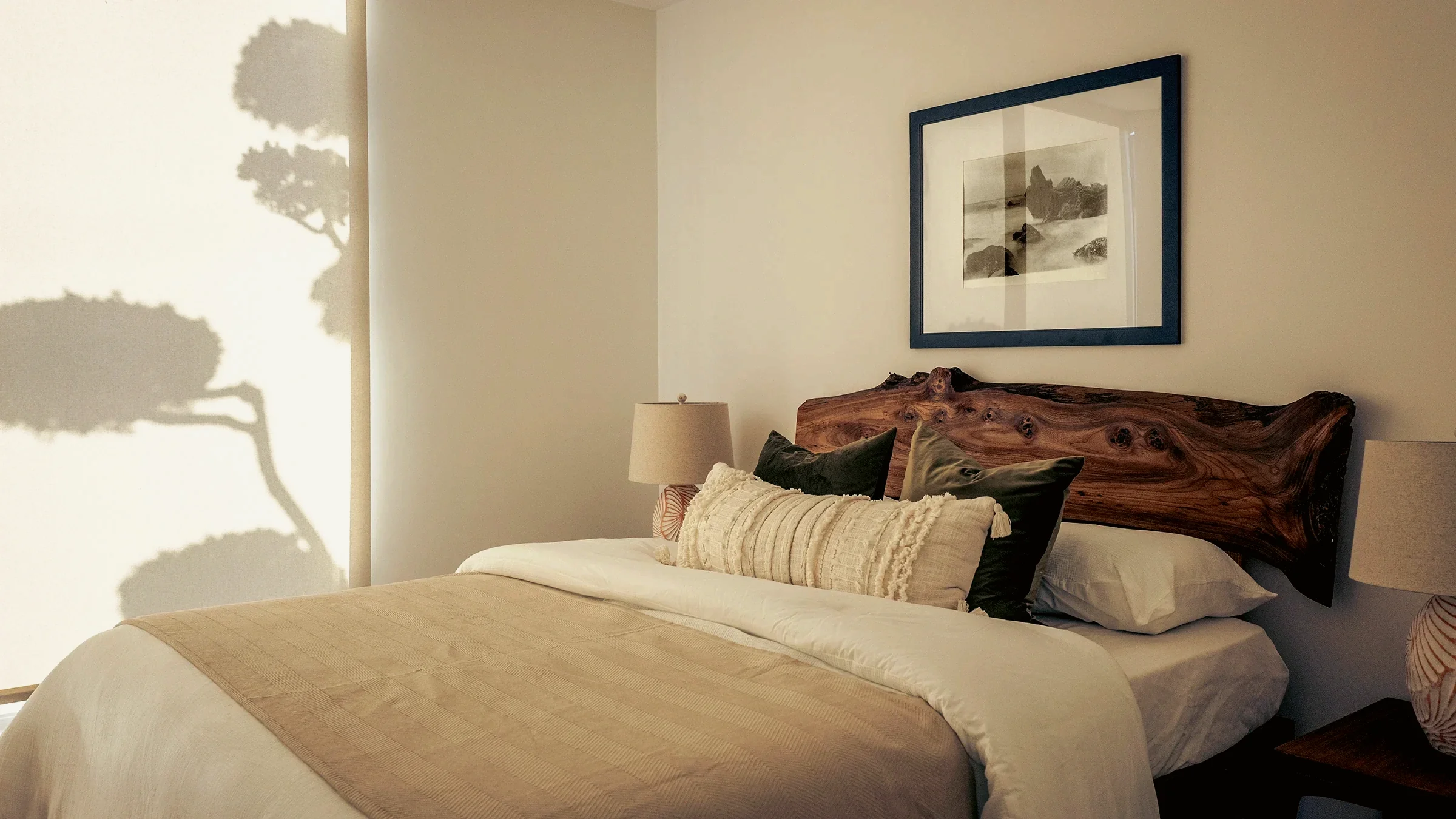 Ladera Heights bedroom in an atomic ranch, with a live-edge walnut headboard and a pine shadow cast across the window shade, staged by Nesting Dolls Design