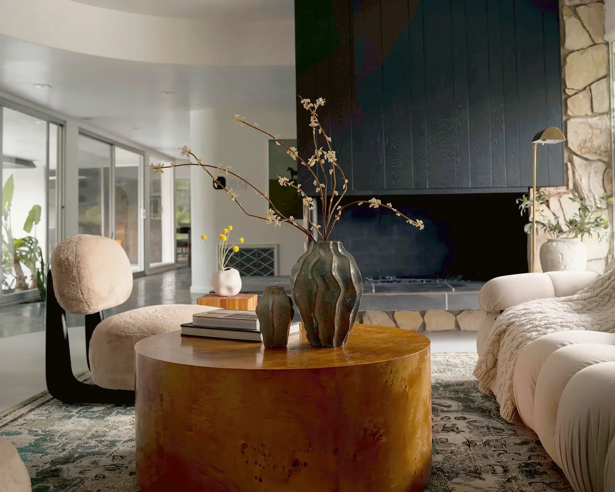View Park living room with an expansive Palos Verdes stone hearth, dark timber chimney breast and a burl wood table, staged by Nesting Dolls Design