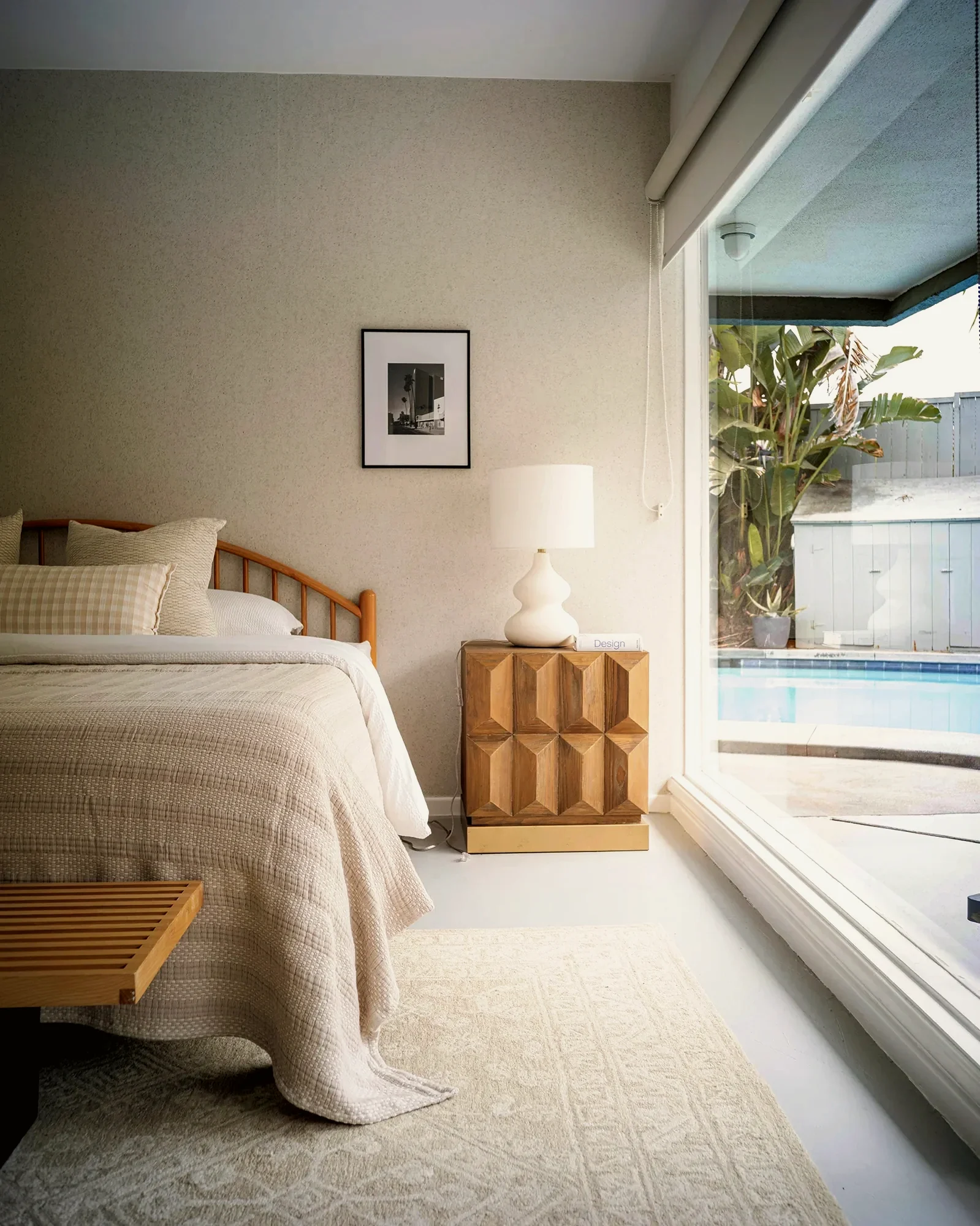 View Park bedroom with a full-height window wall opening onto the pool terrace, staged by Nesting Dolls Design