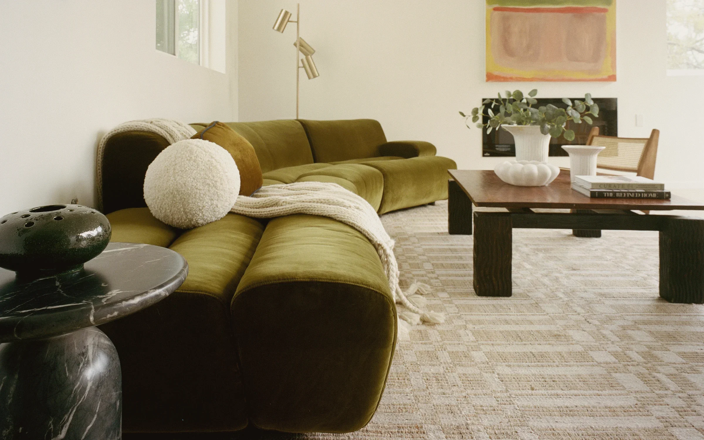 Silver Lake living room in a contemporary infill format, with an olive velvet sofa, a low blackened oak table and a patterned flatweave rug defining the seating zone, staged by Nesting Dolls Design