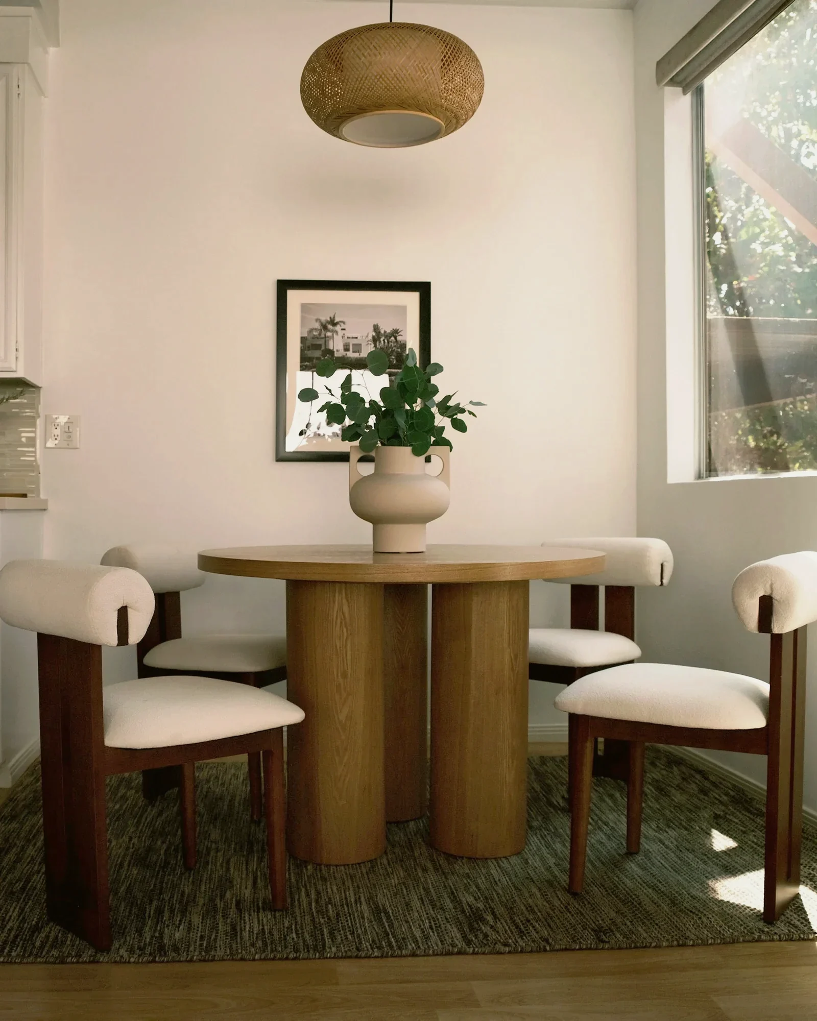 Venice Beach breakfast room with a round oak pedestal table and boucle chairs, staged by Nesting Dolls Design