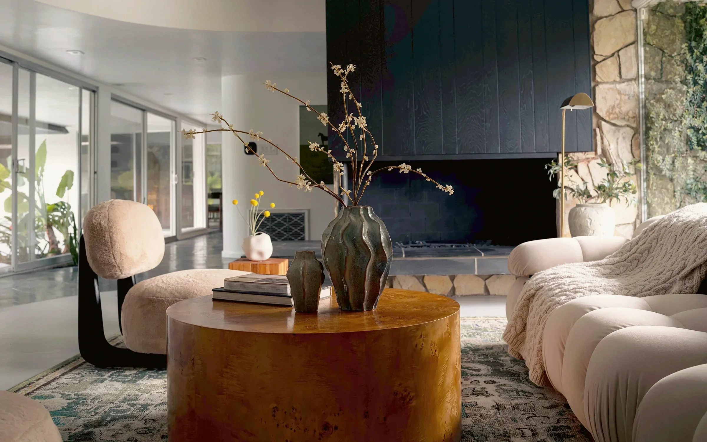 View Park living room with a black board-and-batten chimney breast, original stonework and a round burl coffee table, staged by Nesting Dolls Design