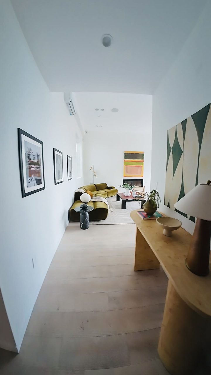Staged Los Angeles living room with an olive velvet sofa, framed artwork and a large abstract canvas, by Nesting Dolls Design